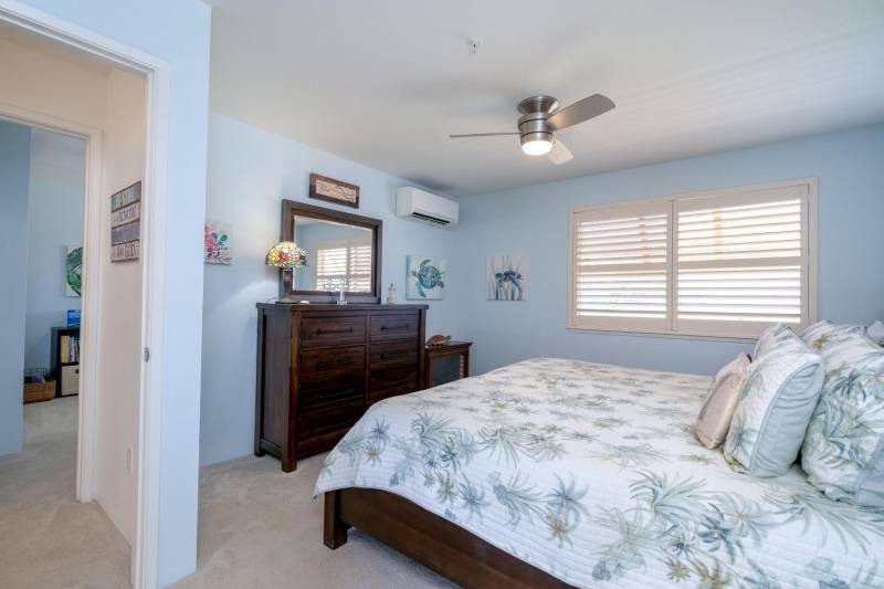 bedroom in kihei maui condi with walls painting pale blue and beige carpet