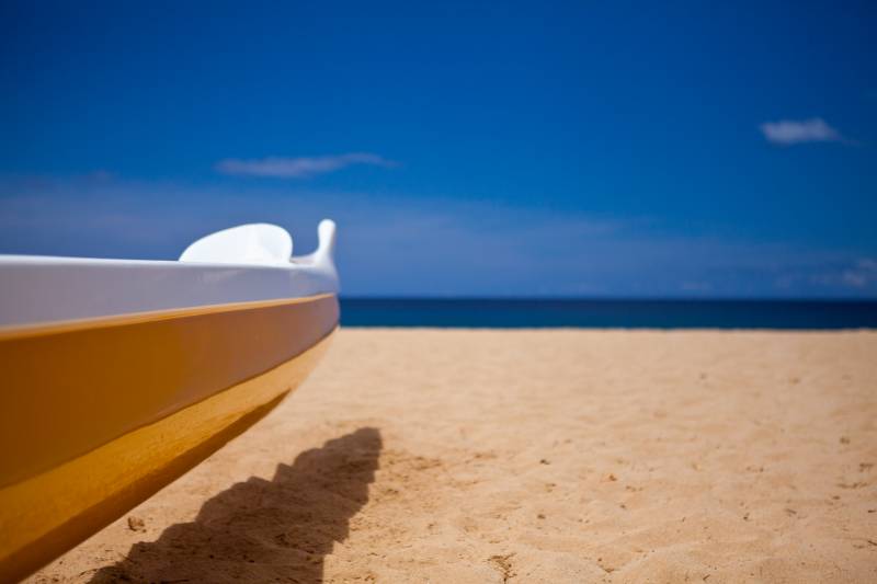closeup of surfboard on wailea maui beach and background of blue sky