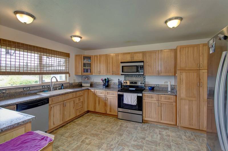 good sized kitchen with wood cabinets, tile floors and stainless steel appliances