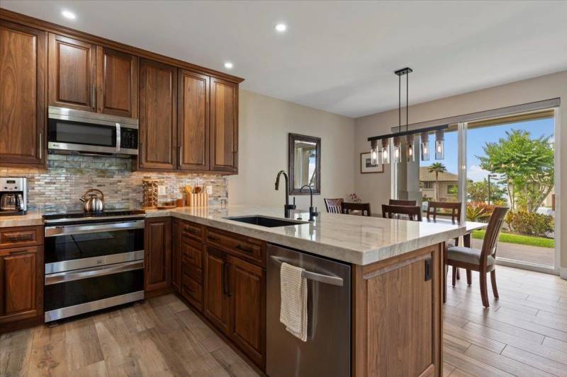kitchen in maui home features dark wood cabinets, quartz countertops, and stainless steel appliances