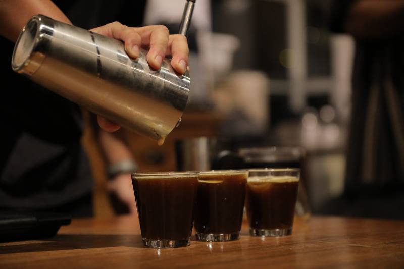 man pouring three glasses of coffee from a stainless steel shaker cup