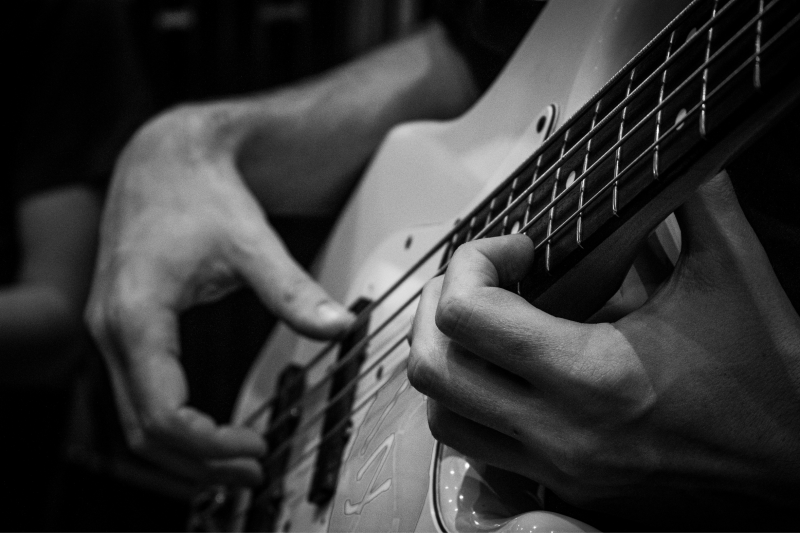 black and white photo of close up of hands playing guitar
