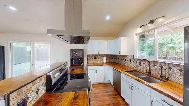 kitchen with wood countertops and white cabinets and tile backsplash