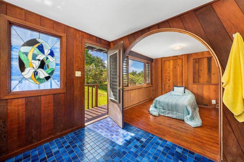 warm wood walls and blue tile in entry with arched door way leading to bedroo 
