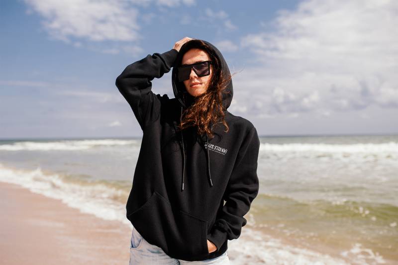 model wearing black maui strong hoodie on the beach