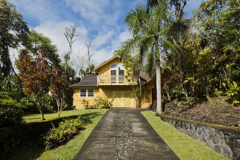 driveway leading to yellow two story home on big island hawaii