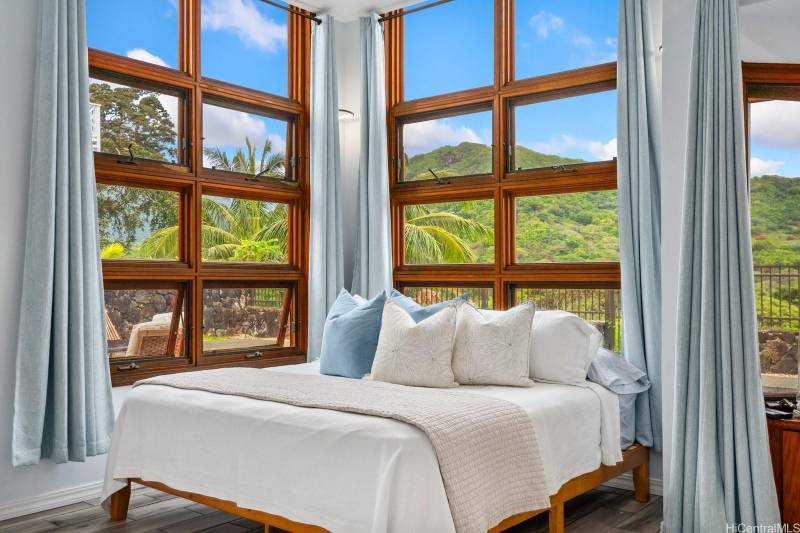 bedroom with walls of windows to capture tropical oahu views