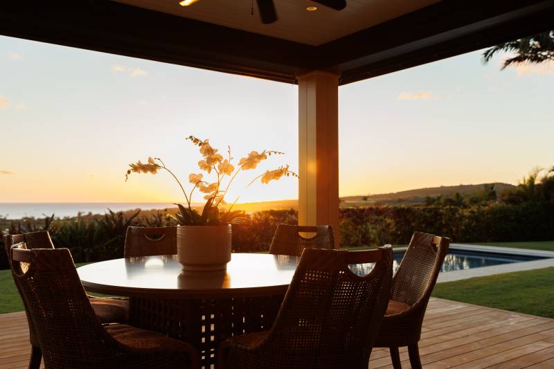 outdoor dining table looking at sunset over the ocean at kukuiula home on kauai