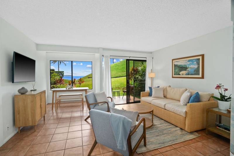 living room in kauai condo for sale with tile floors, beige sofa and cream colored chairs