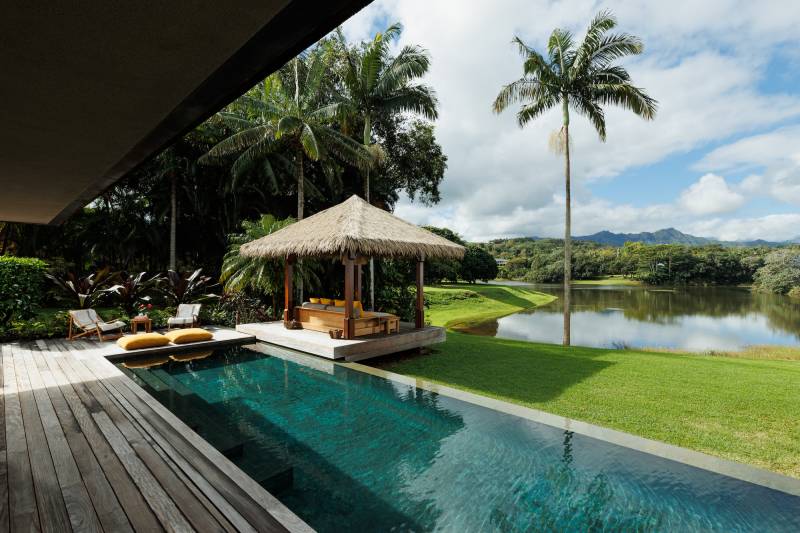view from pool deck of north shore kauai estate looks toward mountains and lush vegetation in the distance
