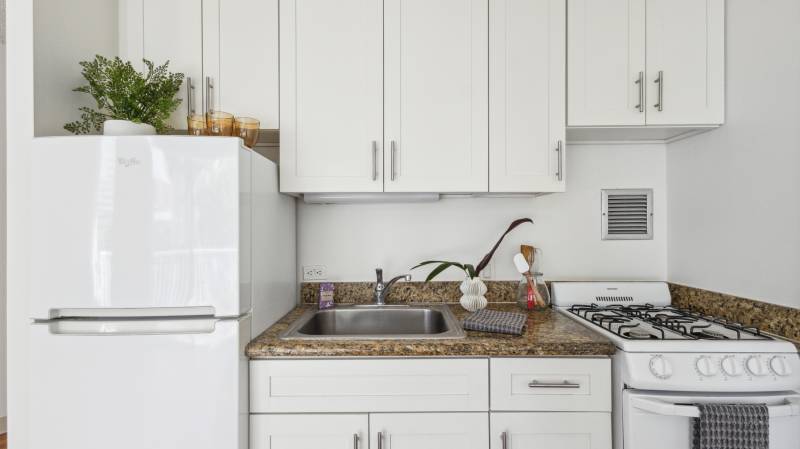 small but efficient condo kitchen featuring white cabinets and white appliances
