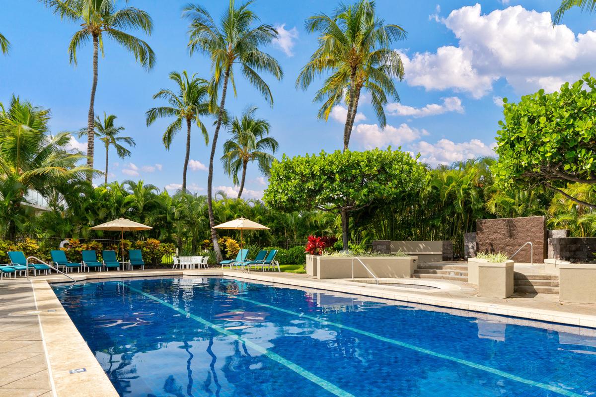 blue pool with lounge chairs in waikoloa big island condos