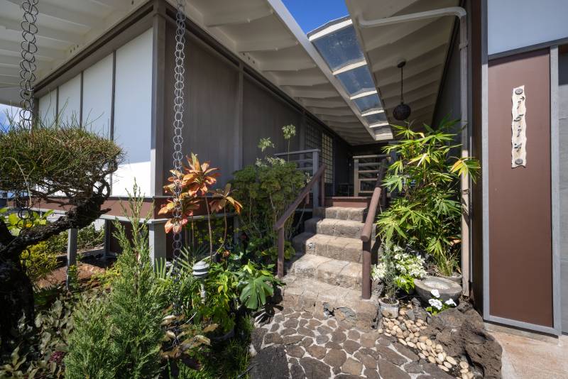 stairs to home entrance with tropical landscaping