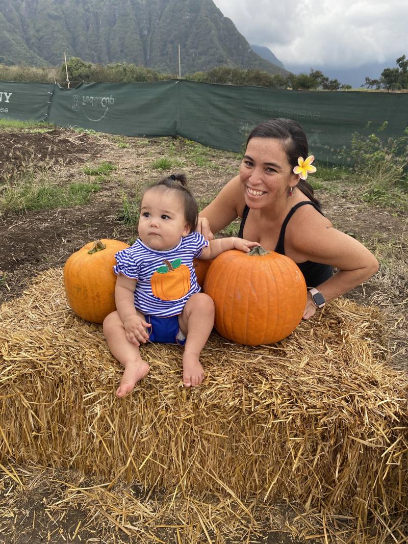 baby sitting on strawbale with pumpkins