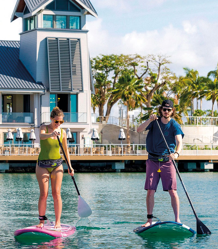 man and woman paddleboard in wai kai waterfront area on oahu