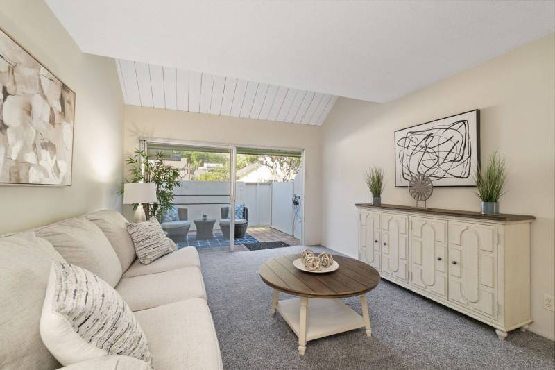 condo living room decorate in white in cream with wood accents on coffee table