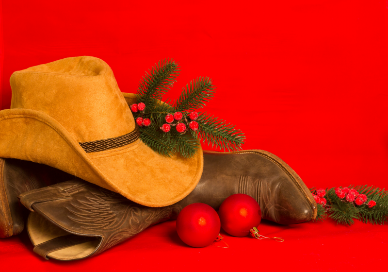 cowboy boots and hat with christmas ornaments and greenery