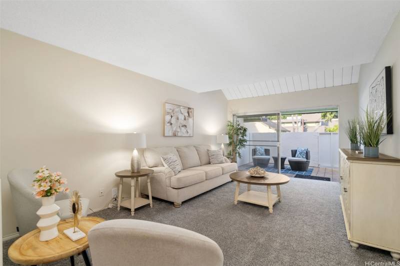 living room with gray carpet and cream sofa. sliding glass doors to lanai