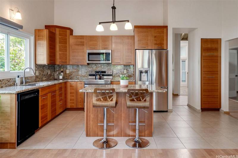 kitchen with warm wood cabinets and island with two barstool seats