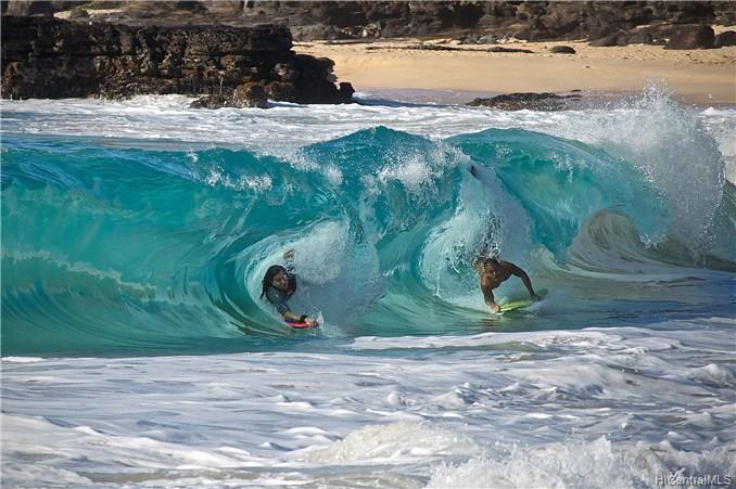 two people surfing a wave