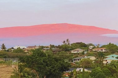 夕焼けに染まるマウナケア山と天文台を望む、ハワイ島ワイコロアビレッジの住宅街の景色