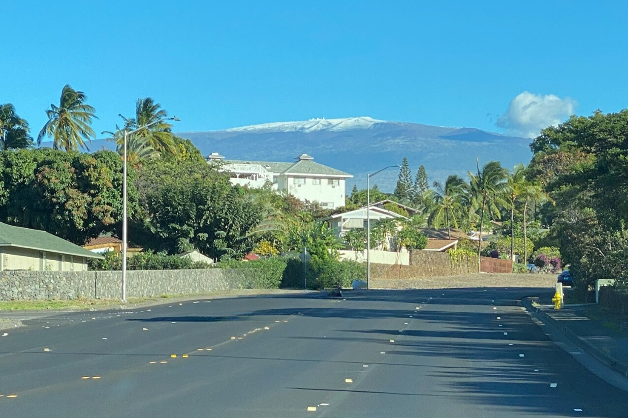 ハワイ島マウナケア山頂に雪が積もった冬の風景。南国の住宅地と雪山のコントラストが印象的