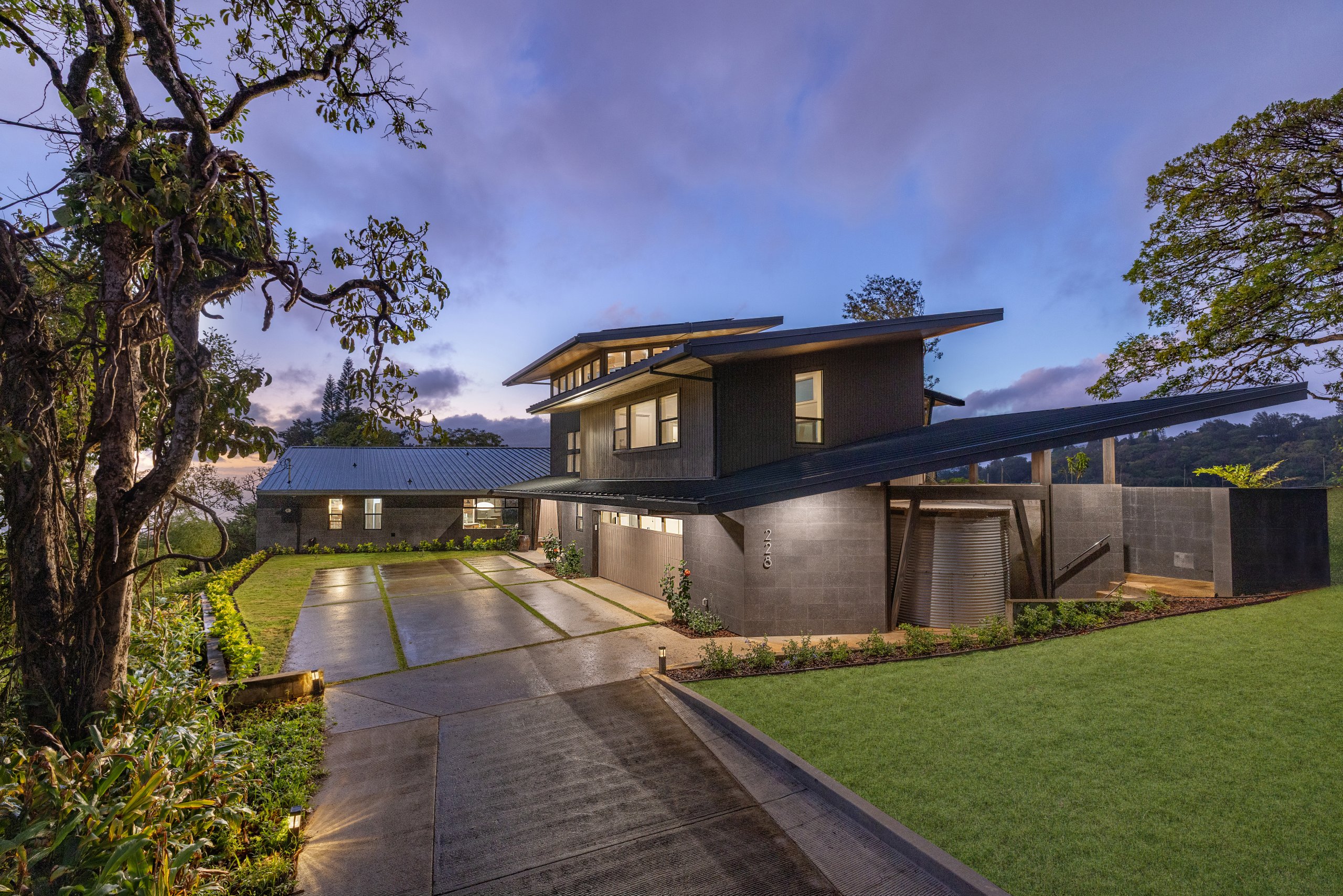 Twilight view of modern home with glowing interior against expansive island landscape