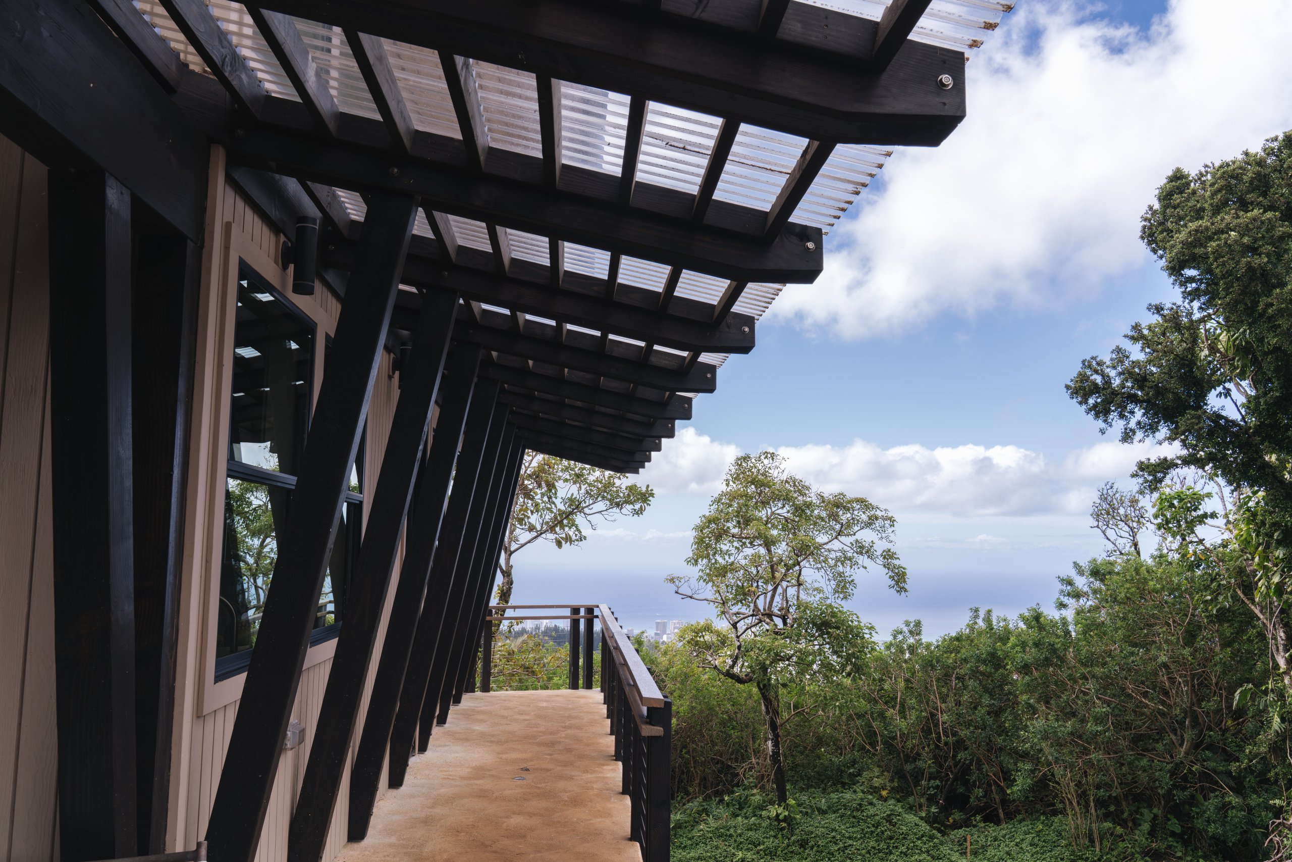 Exterior view showing concrete, wood, and stone materials blending with the natural surroundings
