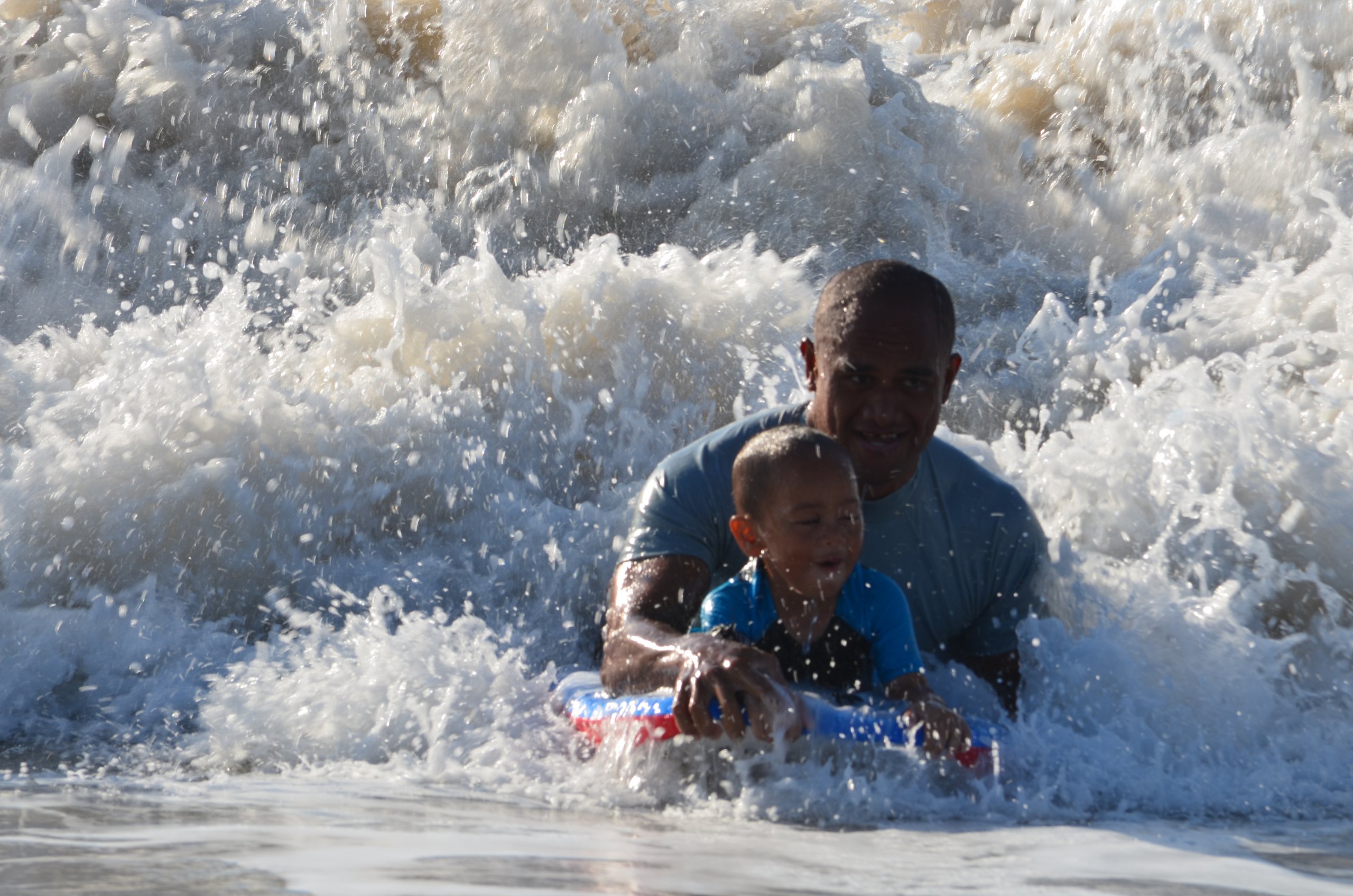 Father and son riding a boogie board.