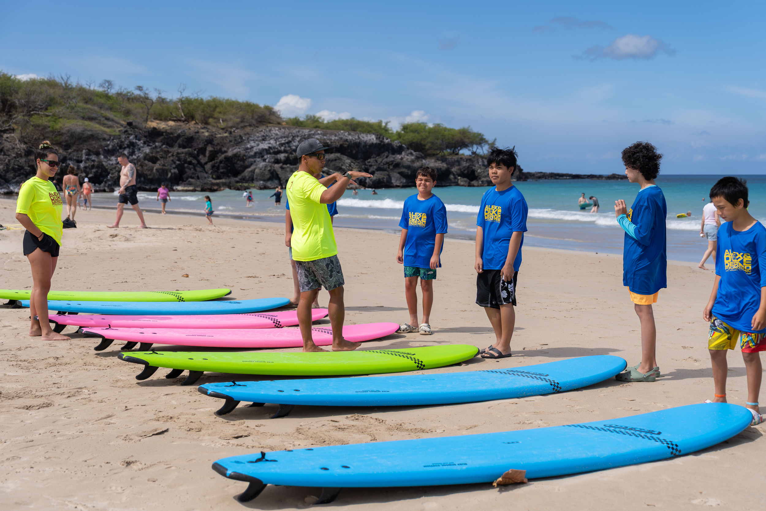 Surf instructor guides kids on a beach.