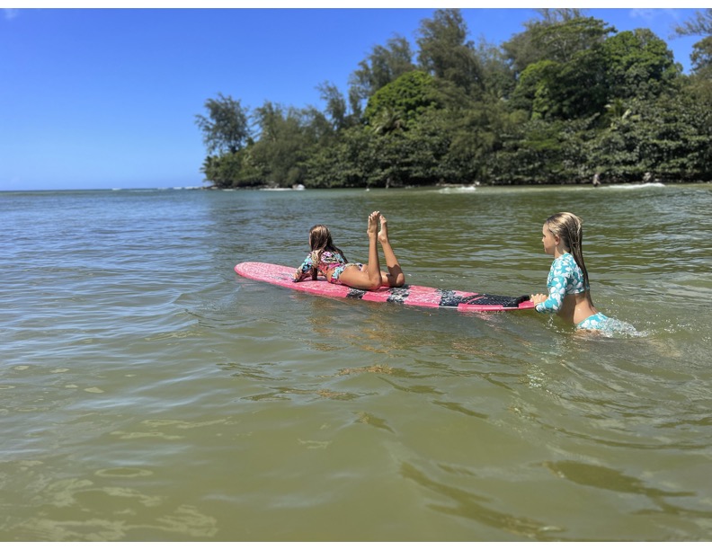 two girls on surfboards in the ocean on kauai
