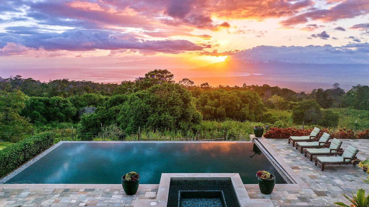 Resort-style pool and spa area at sunset with cabana and sweeping Maui views